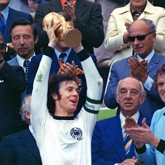 Franz Beckenbauer hebt einen Pokal in die Luft.