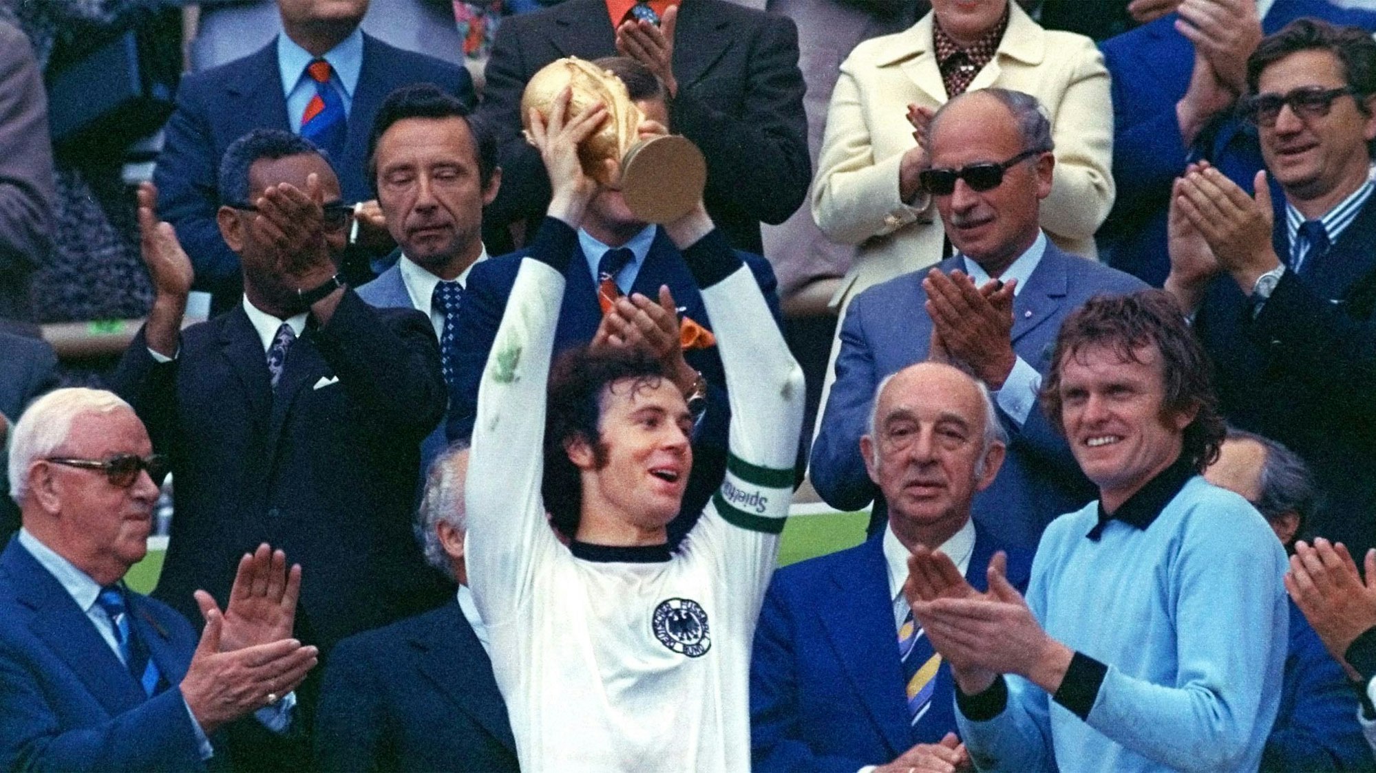 Franz Beckenbauer hebt einen Pokal in die Luft.