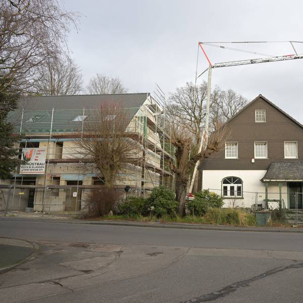 Rechts steht der Altbau, links daneben der Rohbau mit für ein Doppelhaus mit Gerüst.