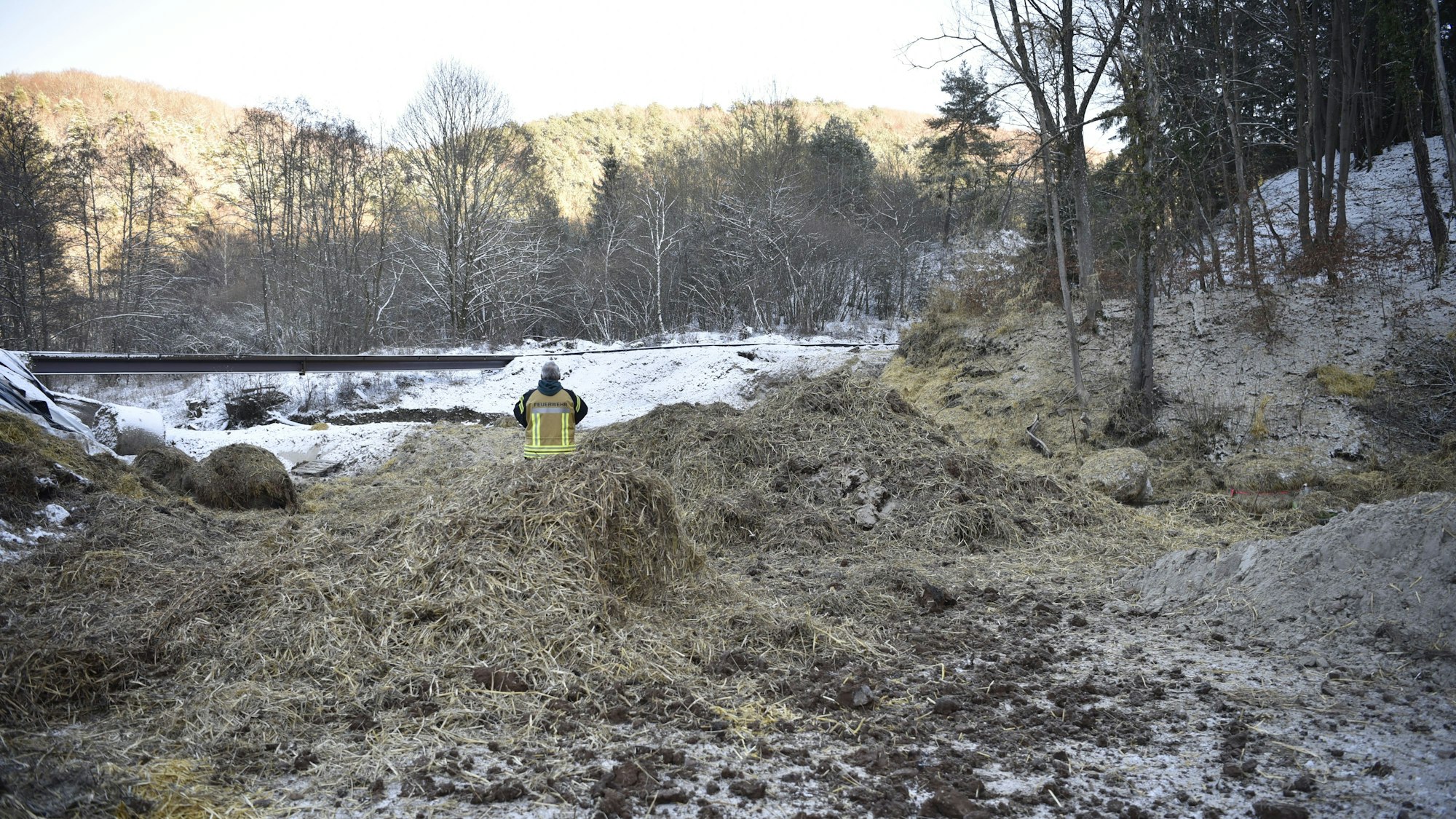 Nach der Sprengung einer Weltkriegsbombe liegt Stroh in der Nähe der Bahnlinie. Ein Feuerwehrmann beobachtet die Szenerie.