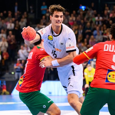 Handballer Julian Köster spielt im deutschen Nationaltrikot. Er setzt sich gegen zwei Gegner aus Portugal durch.