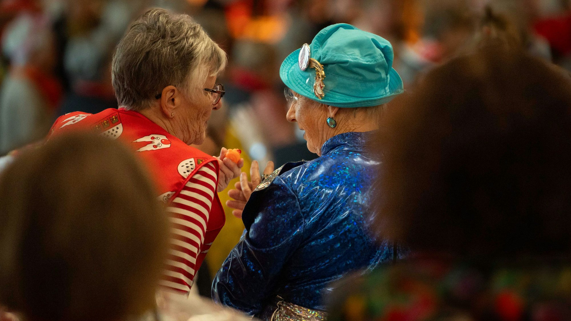 Das Bild zeigt zwei Seniorinnen, eine von ihnen hält eine orange Quietsche-Entchen in der Hand.