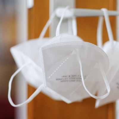 FP2-Masken hängen an einer Türklinke.