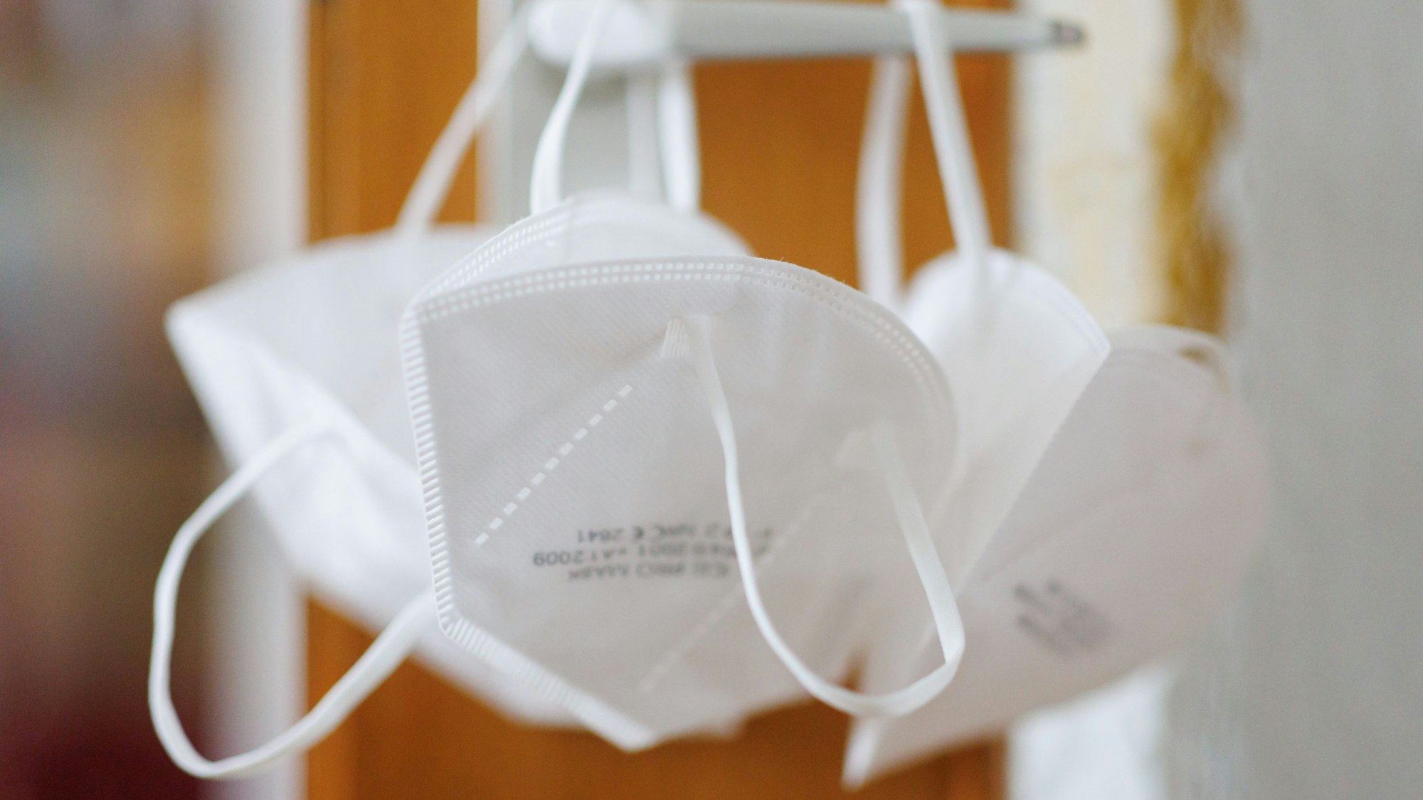 FP2-Masken hängen an einer Türklinke.