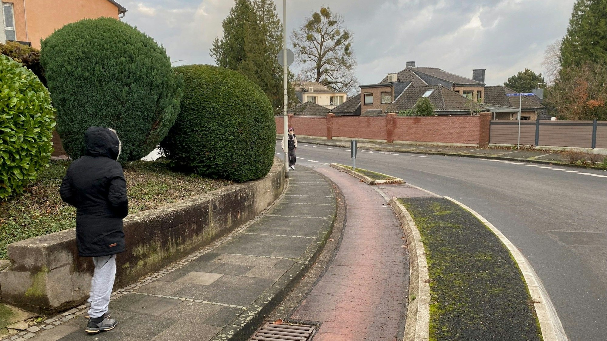 Zu sehen ist die Schulstraße in Kierberg, die eine Kurve beschreibt und über einen abgetrennten Radstreifen verfügt.