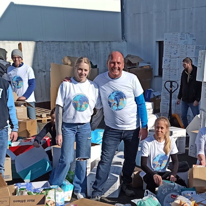 Jürgen Perteck (rechts, Mitte) steht neben anderen Vereinsmitgliedern, die Kartons packen.