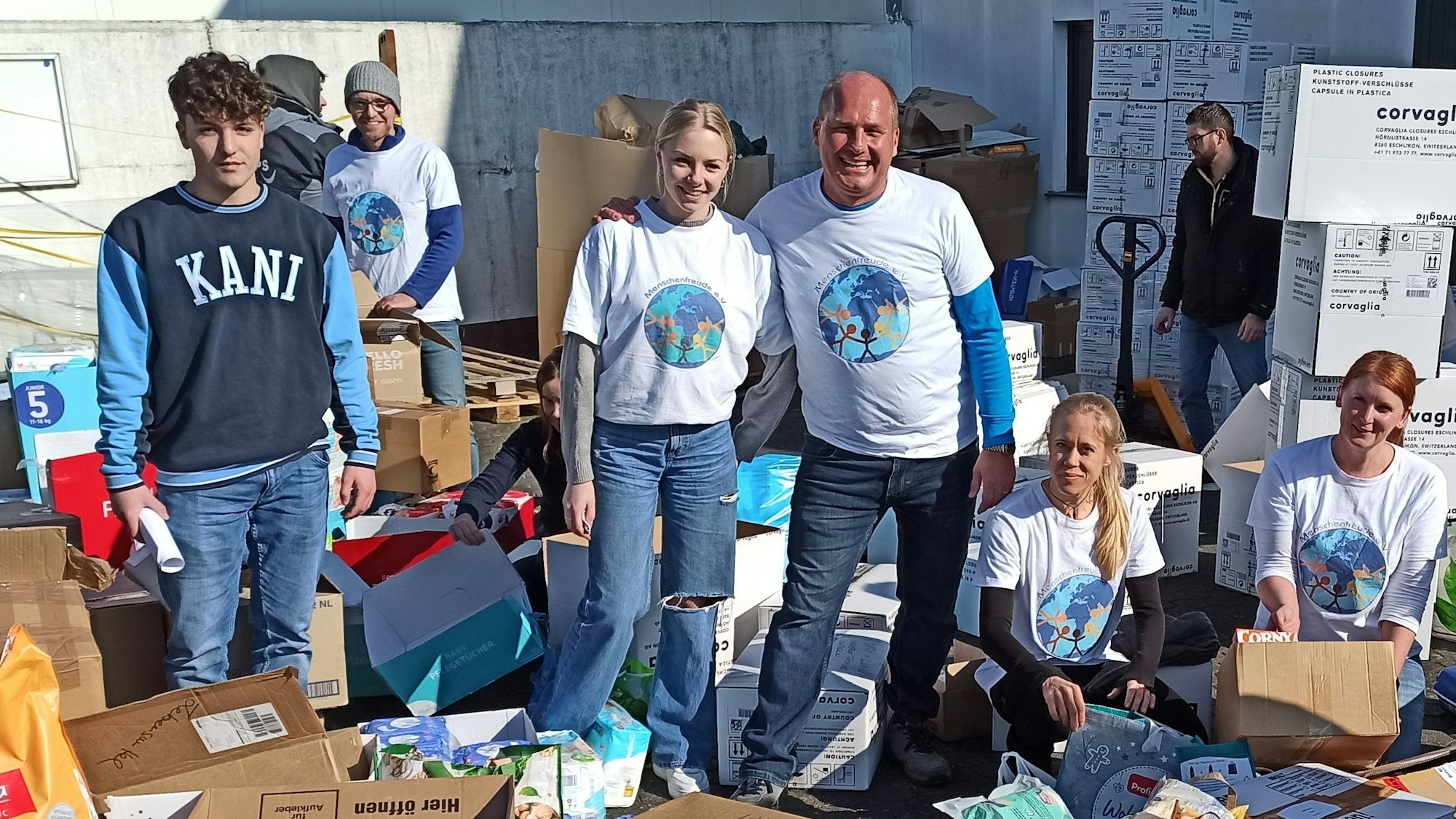 Jürgen Perteck (rechts, Mitte) steht neben anderen Vereinsmitgliedern, die Kartons packen.