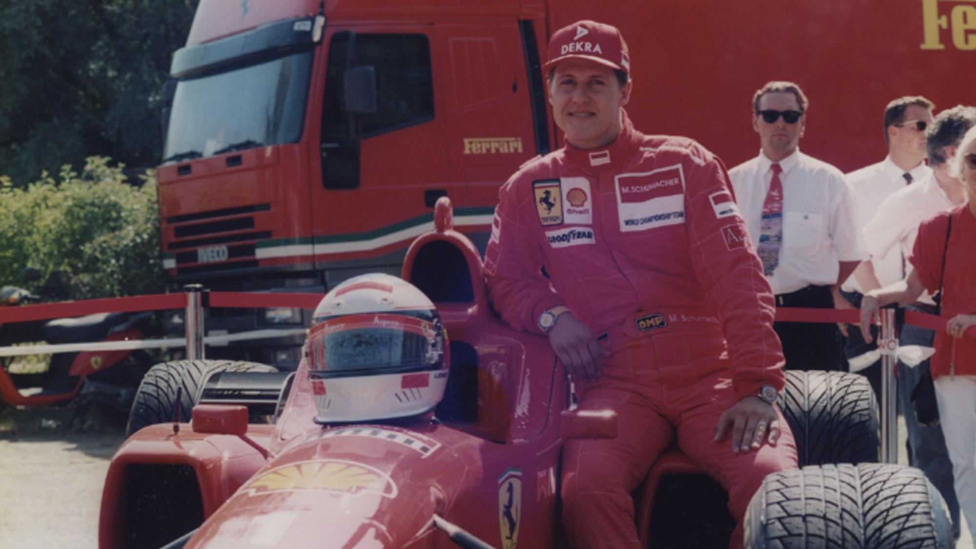 Michael Schumacher lehnt sich an einen Ferrari.