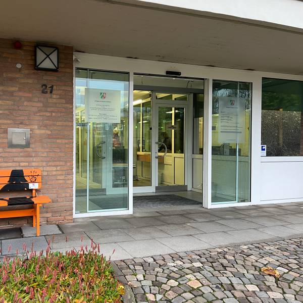 Am Eingang zum Bensberger Amtsgericht steht eine orangefarbene Bank mit der Aufschrift „Kein Platz für Gewalt gegen Frauen“.