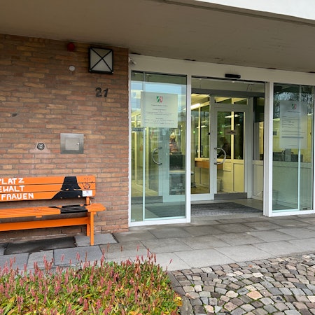 Am Eingang zum Bensberger Amtsgericht steht eine orangefarbene Bank mit der Aufschrift „Kein Platz für Gewalt gegen Frauen“.