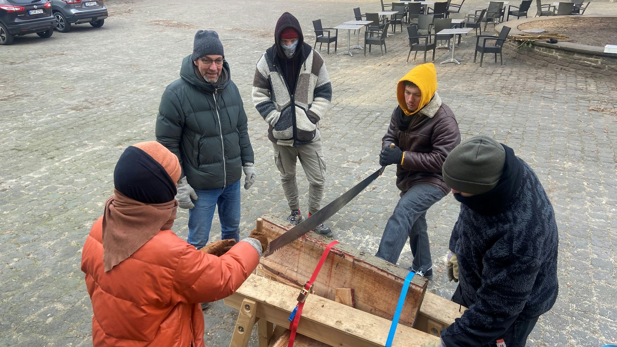 Vor einem Fachwerk-Gebäude sind Holzsäge-Arbeiten im Gange.