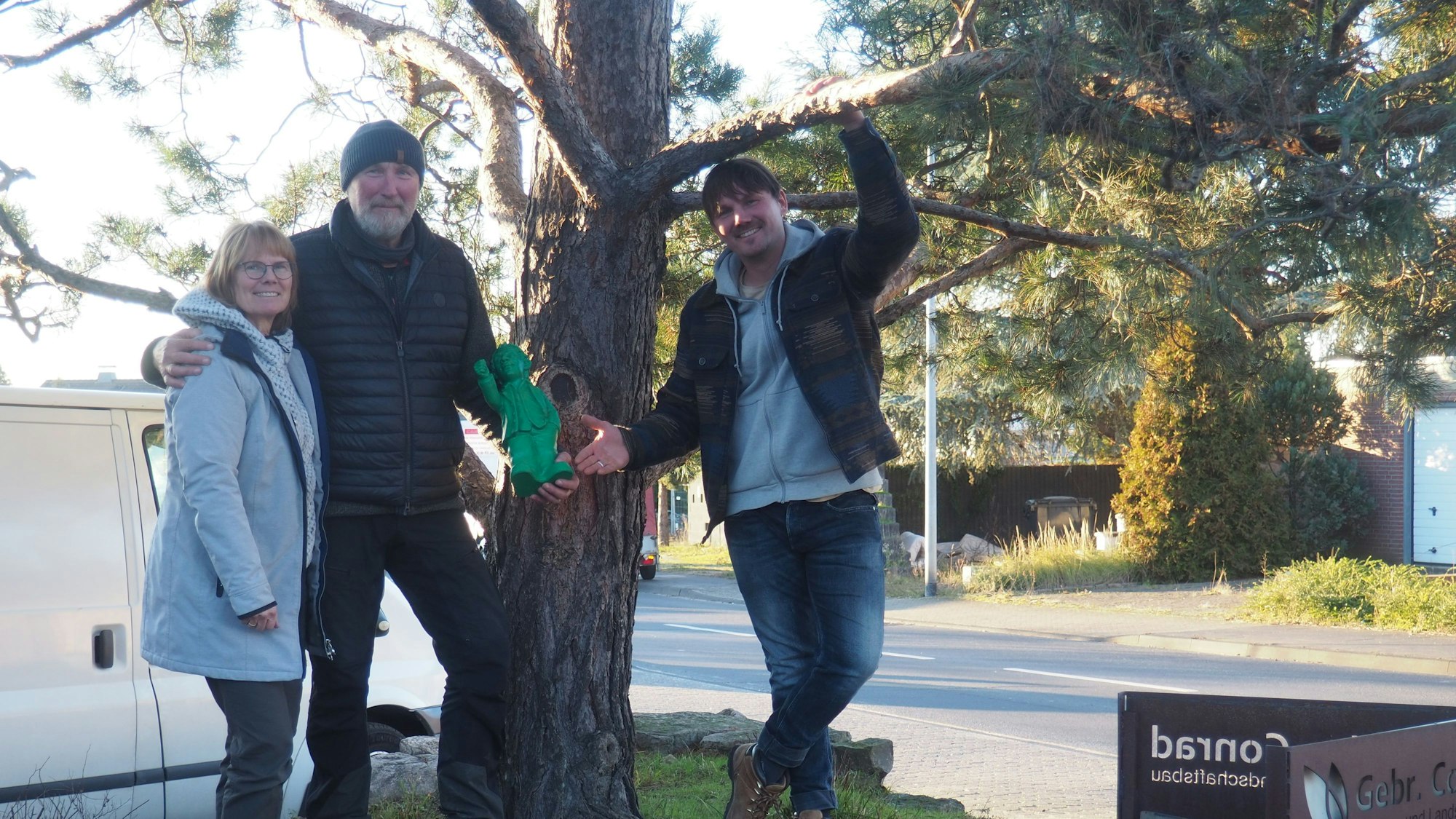Drei Menschen stehen unter einem Baum.
