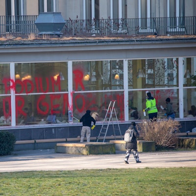 Zwei Personen versuchen, die Scheiben der Universität zu säubern.