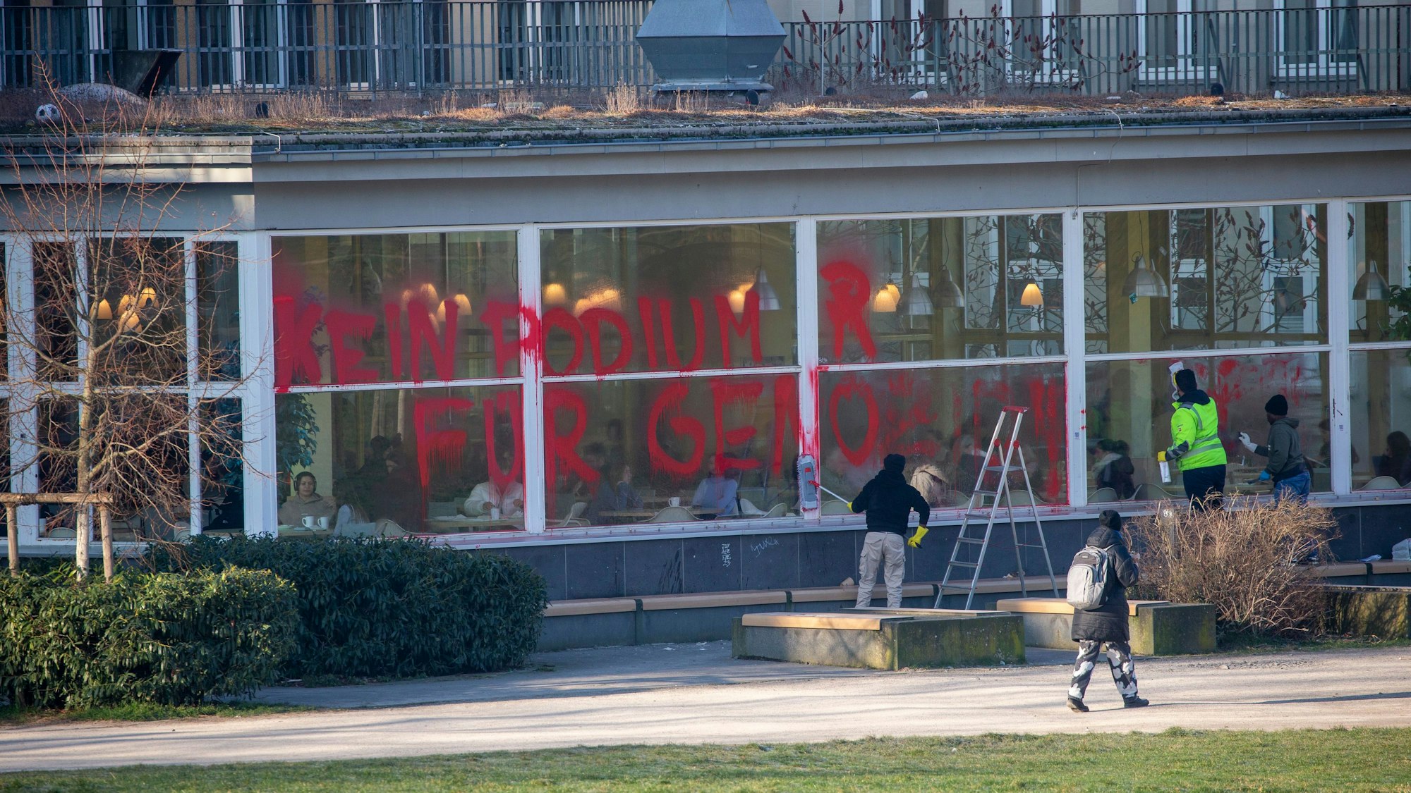 Zwei Personen versuchen, die Scheiben der Universität zu säubern.