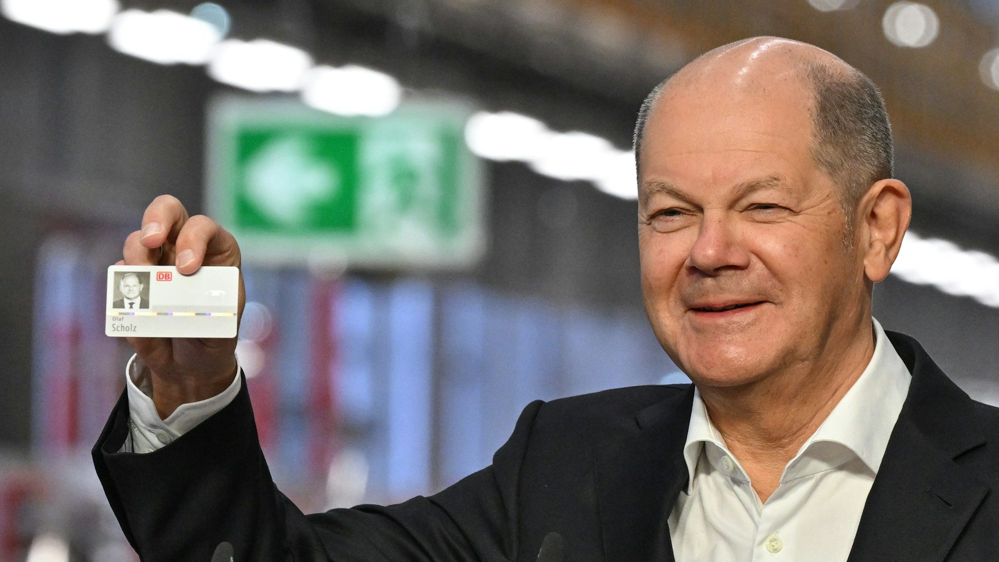 Cottbus: Bundeskanzler Olaf Scholz (SPD) freut sich über einen Mitarbeiterausweis, den er zur Eröffnung vom DB-Instandhaltungswerk geschenkt bekommen hat.