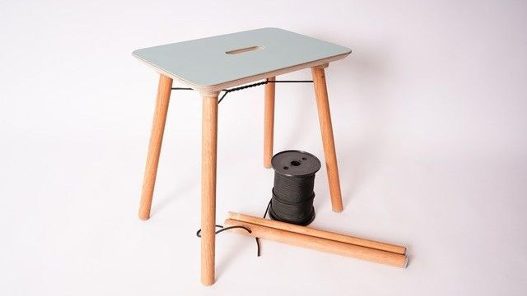 Hocker mit Spule auf vier Holzbeinen.