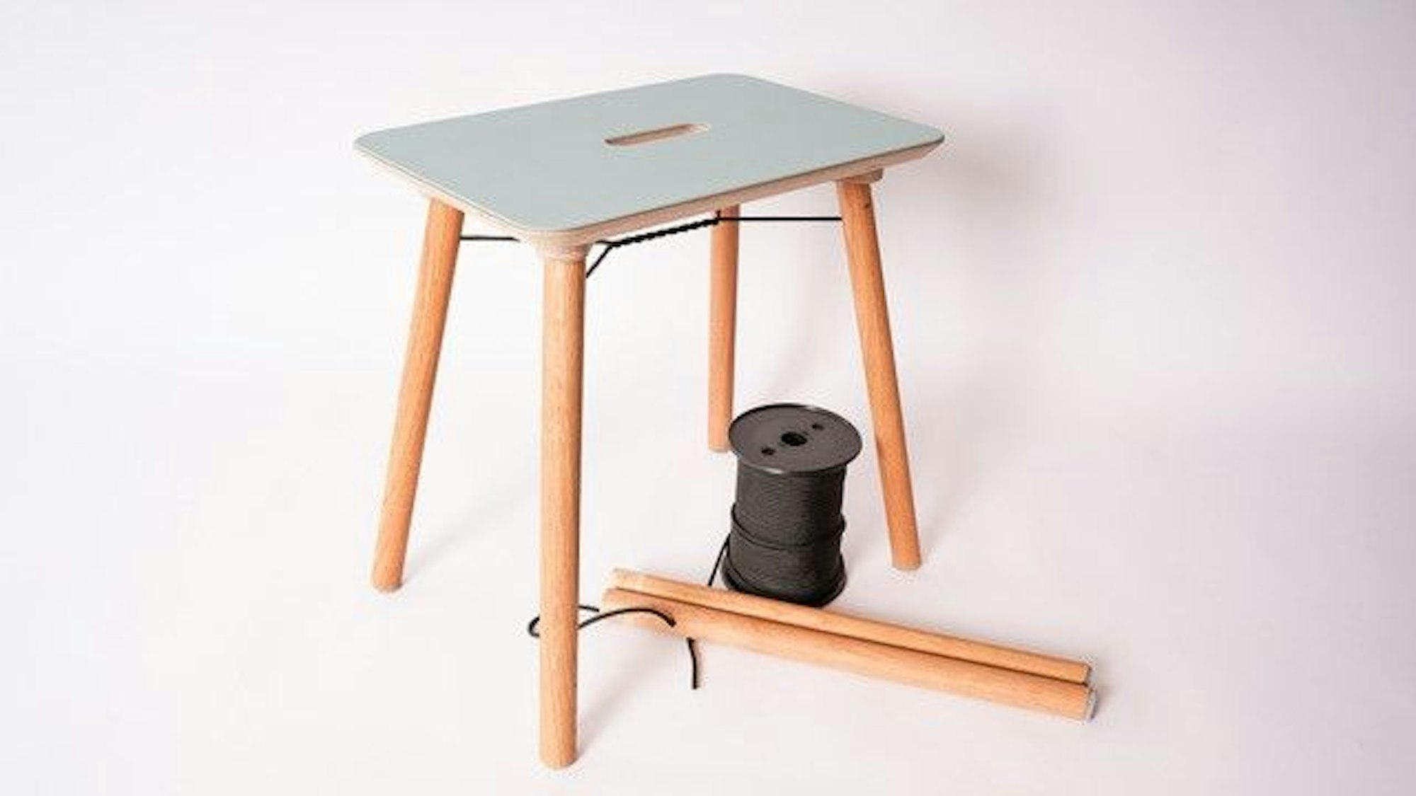 Hocker mit Spule auf vier Holzbeinen.