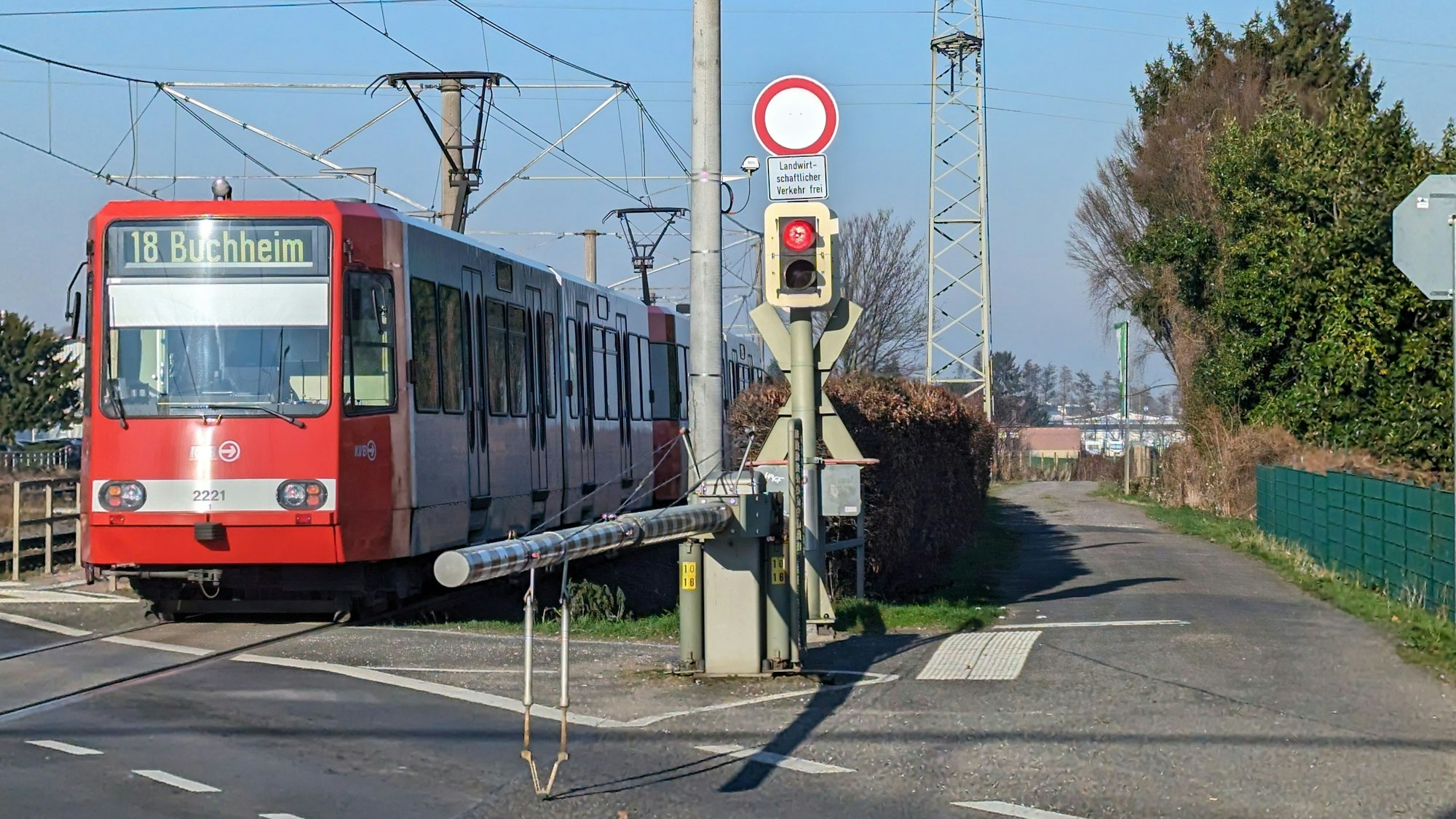 Eine Stadtbahn fährt in den Haltepunkt Fischenich ein, neben den Gleisen ein Wirtschaftsweg.