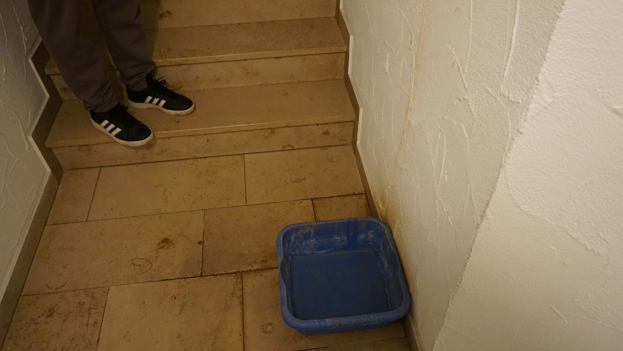 Eine blaue Wanne steht im Flur. Sie fängt Tropfwasser auf.