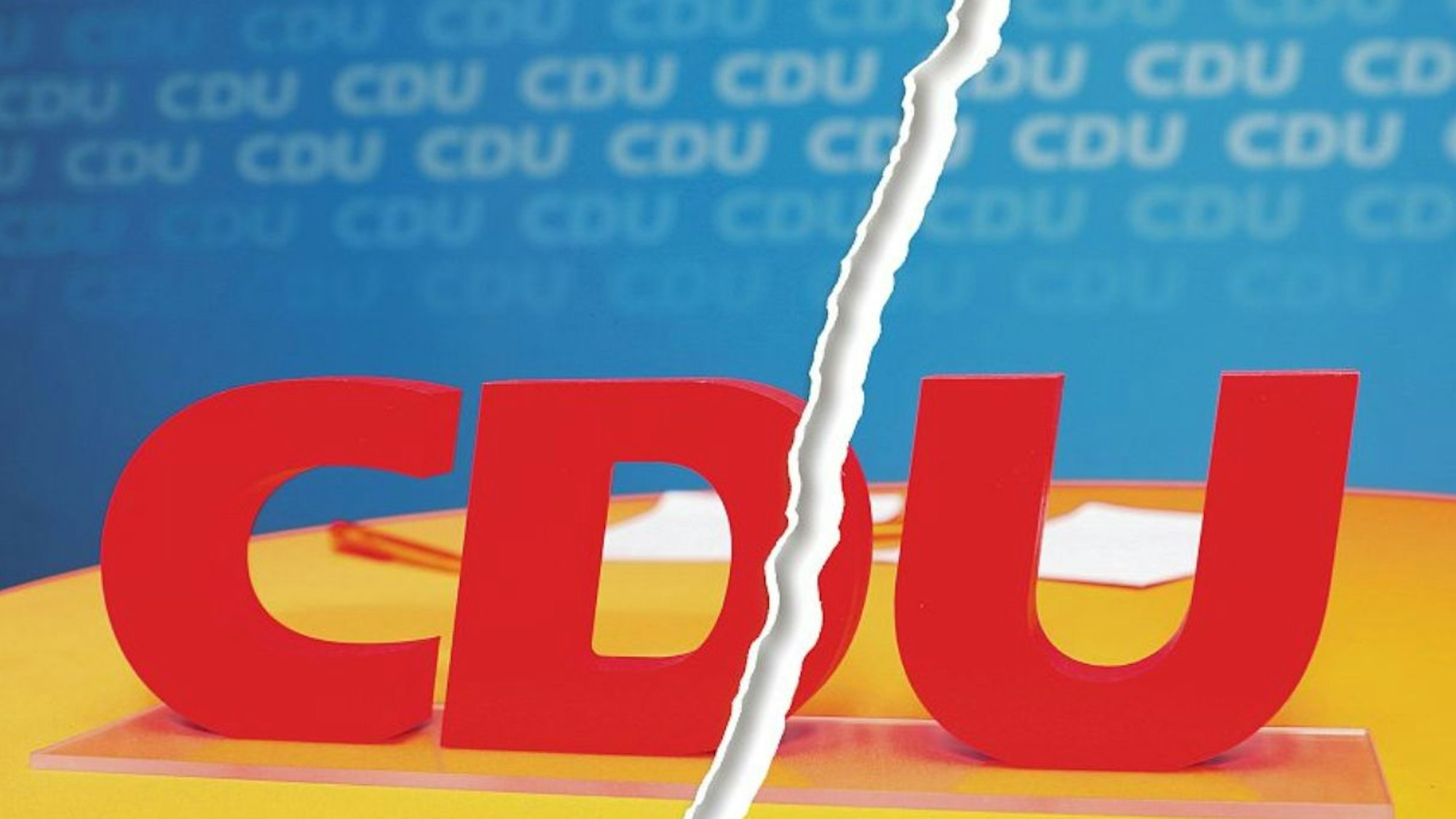 Ein Riss geht durch ein Bild vom Schriftzug CDU bei einem Kreisparteitag der CDU Rhein-Berg.