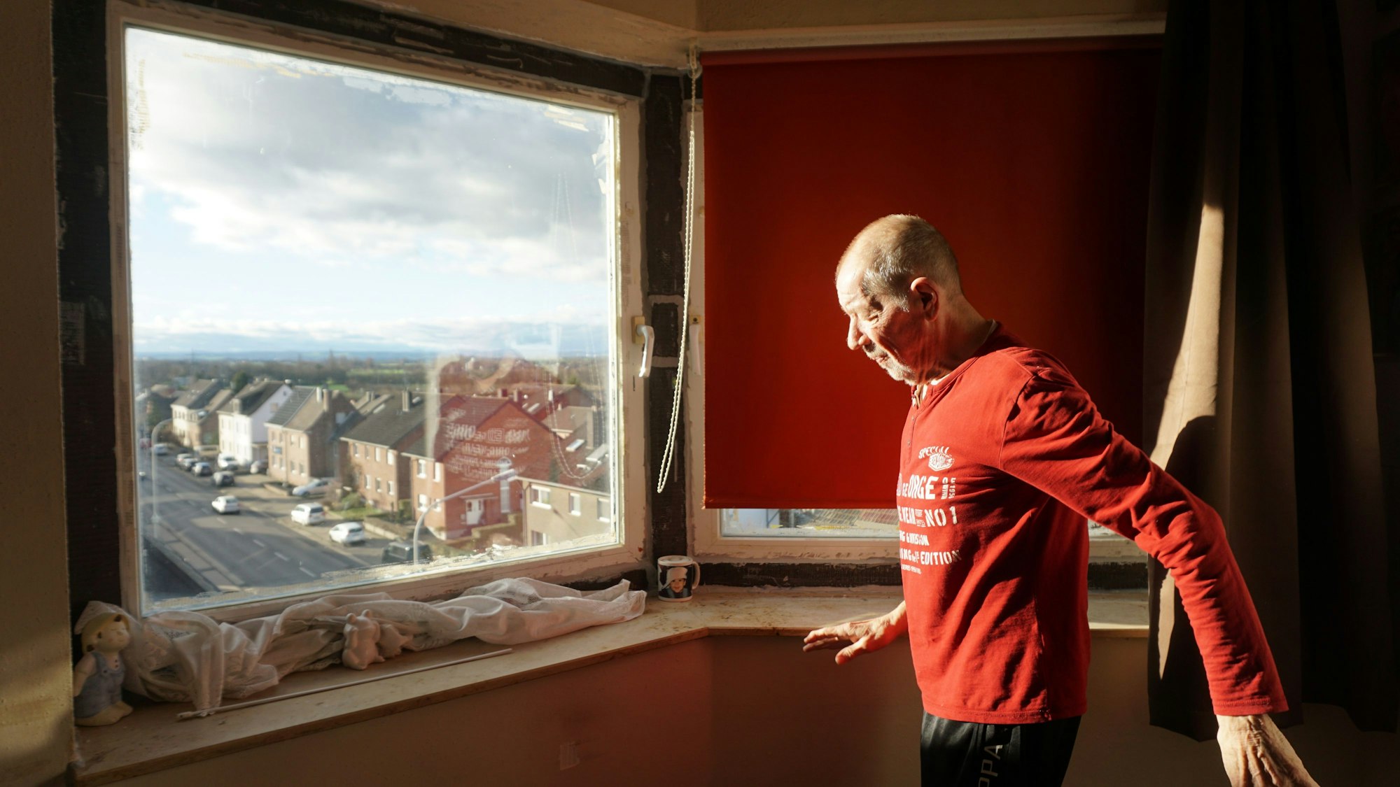 Josef Schwingeler steht vor seinem Fenster mit Blick auf eine Weilerswister Straße.