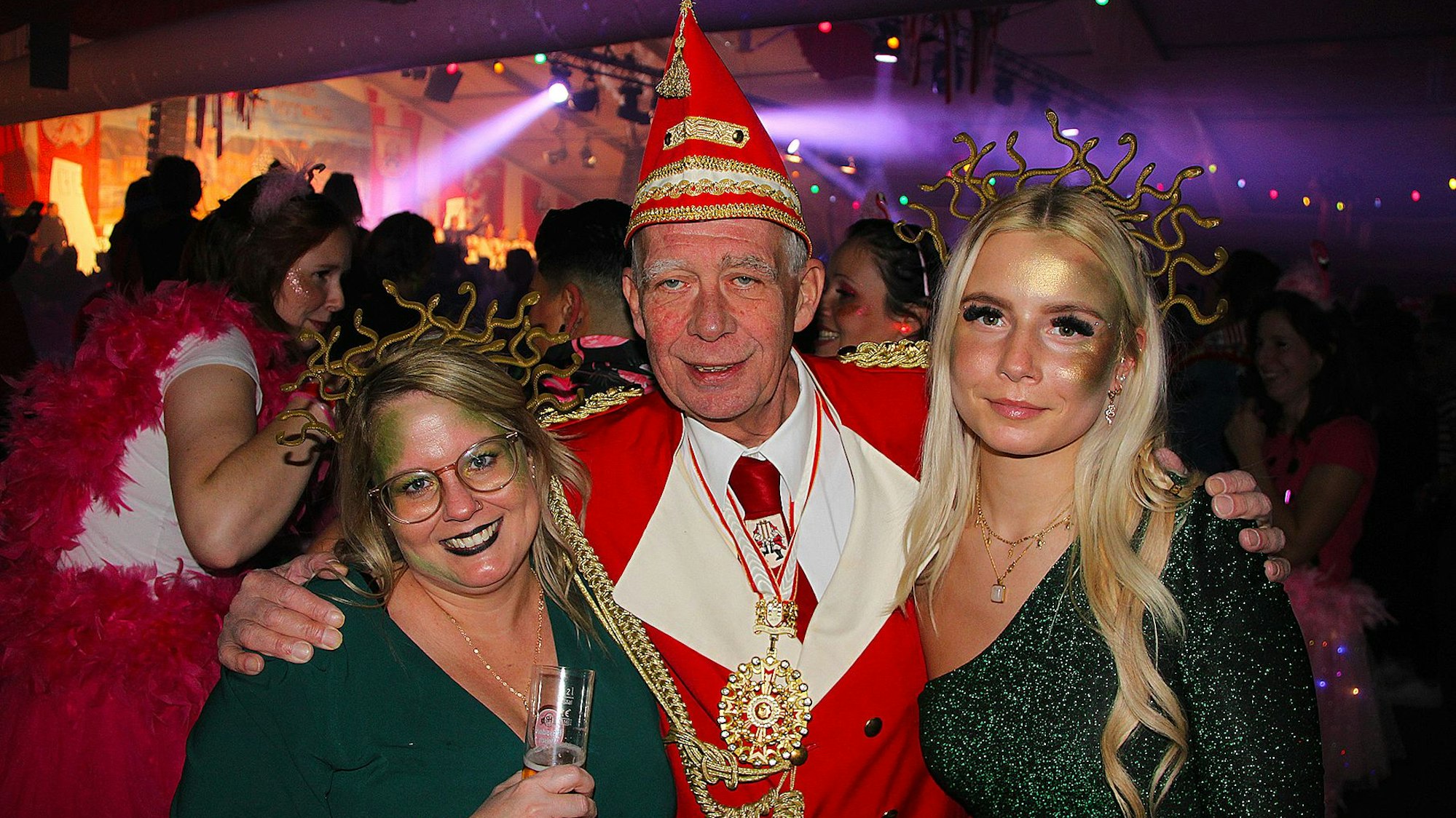 KG-Präsident Udo Kreitz hält die als Medusen verkleideten Frauen Sabina und Laura im Arm.