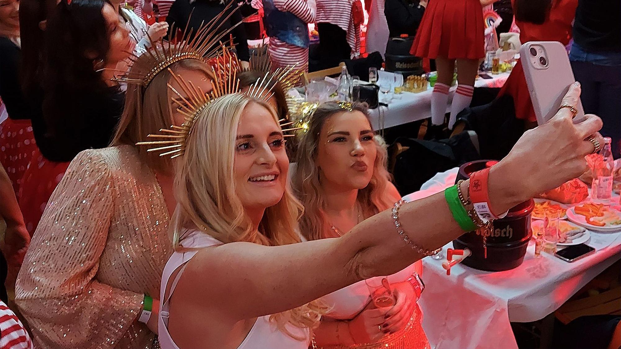 Drei als Sonnengöttinnen verkleidete Frauen machen ein Selfie.