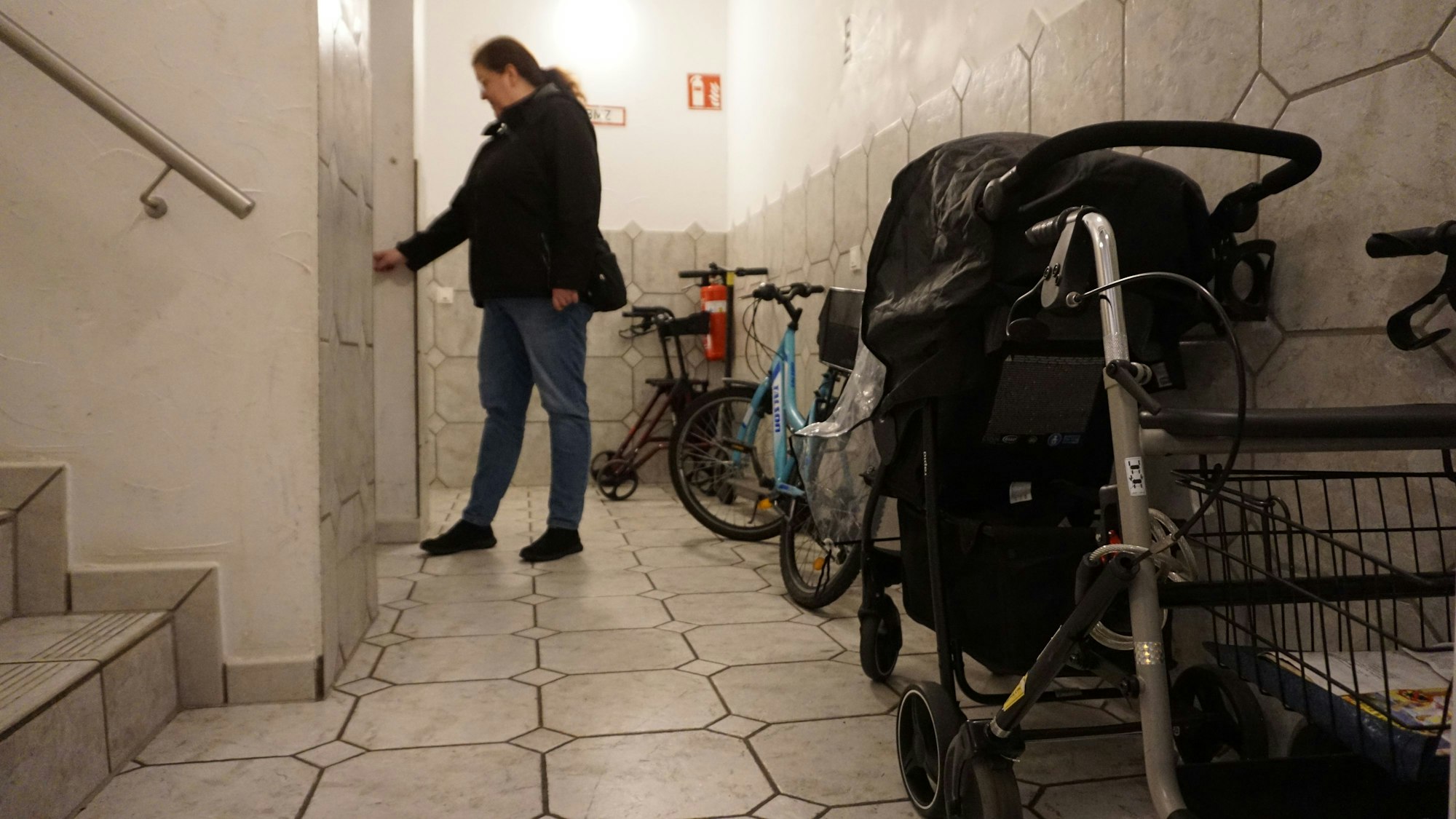 Eine Frau wartet im Flur auf den Aufzug.