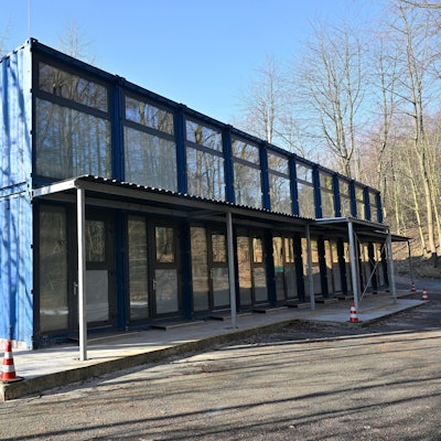 Blaue Schiffscontainer werden zu Geflüchtetenunterkünften umgebaut.