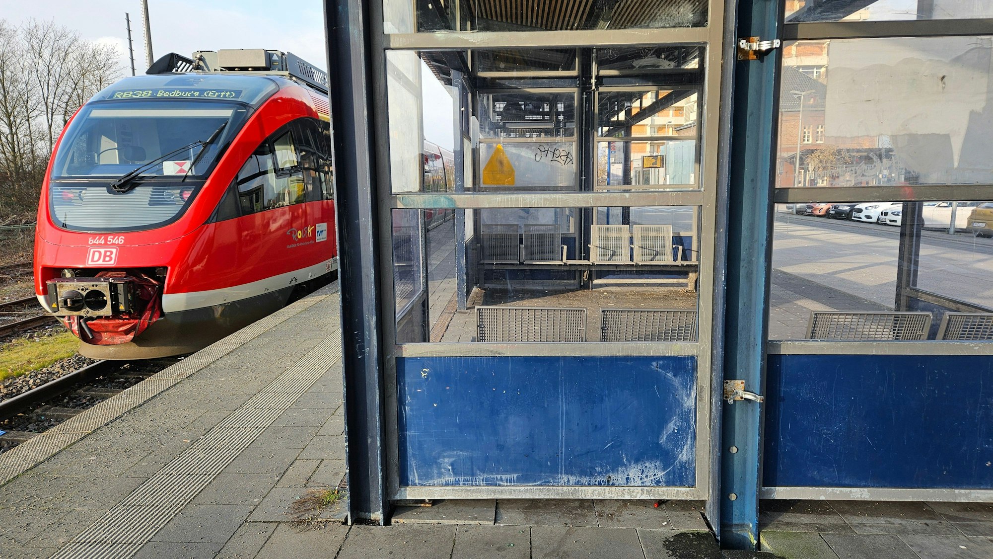 Ein Zug steht an einem Bahnsteig, im Wartehäuschen sind viele Scheiben zerschlagen.