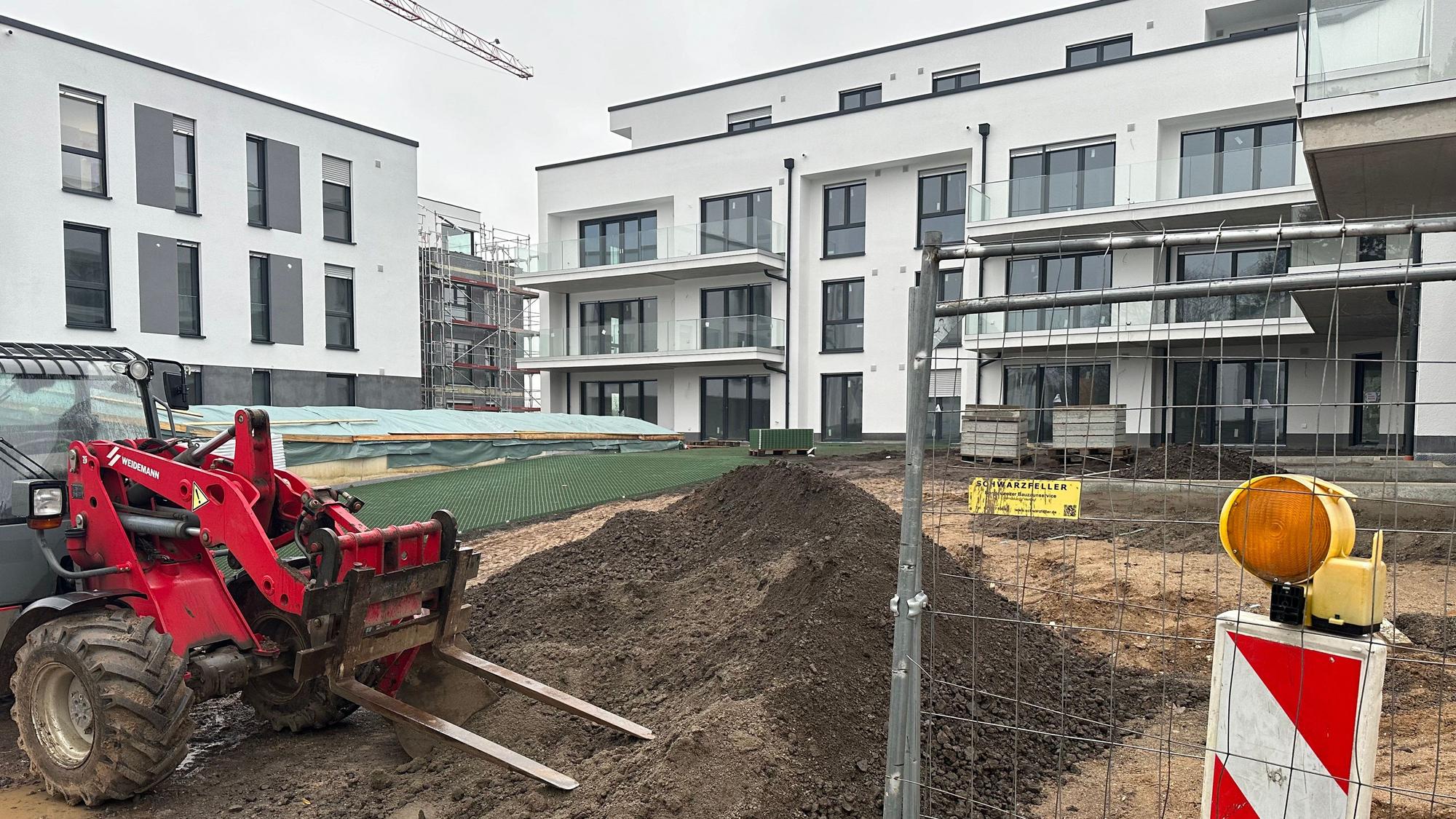 Auf dem Baugrundstück eines Mehrfamilienhaus-Projekts steht eine Baumaschine.