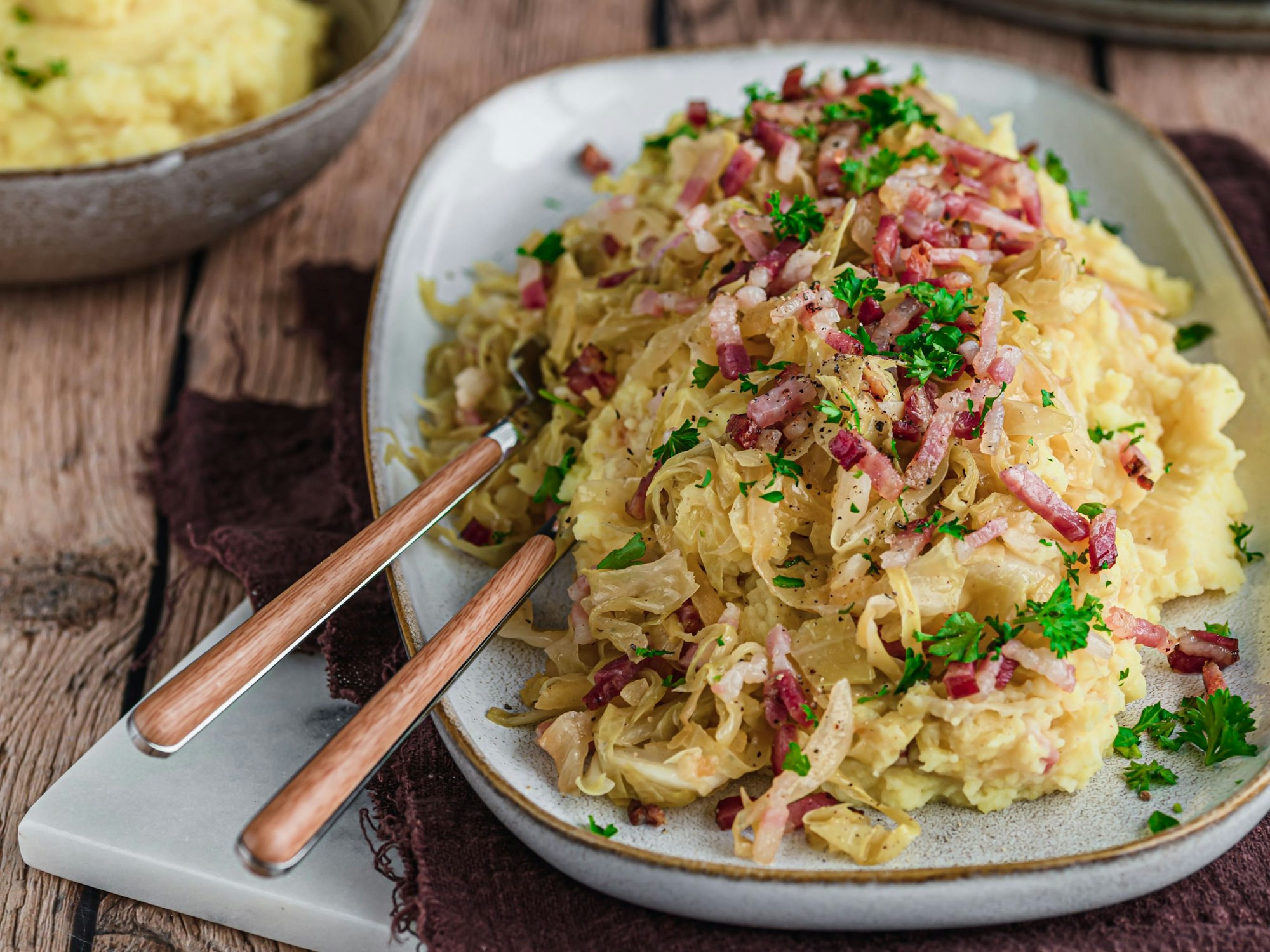 Kraut, Kartoffelbrei und Speck auf einem Teller serviert.