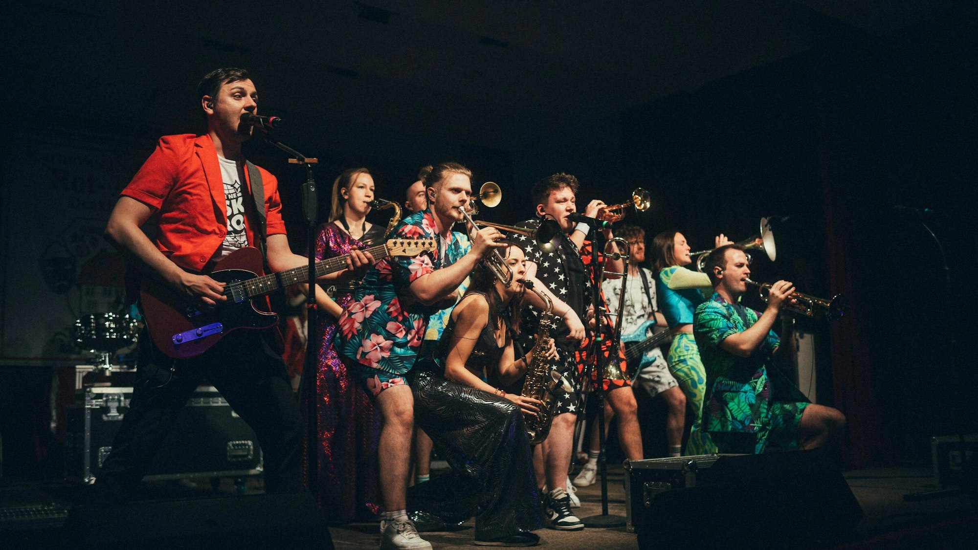 Auf der Bühne begeistert Druckluft das Publikum mit einer coolen Show und flotten Brassrhythmen. In der Mitte Interviewpartner Florian Hertel im Schwarzen Outfit mit weißen Sternen.