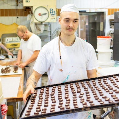 Der Bäcker Louis Braun trägt in der Bäckerei und Konditorei Lobenstein ein Blech voller Plätzchen zum Backofen.