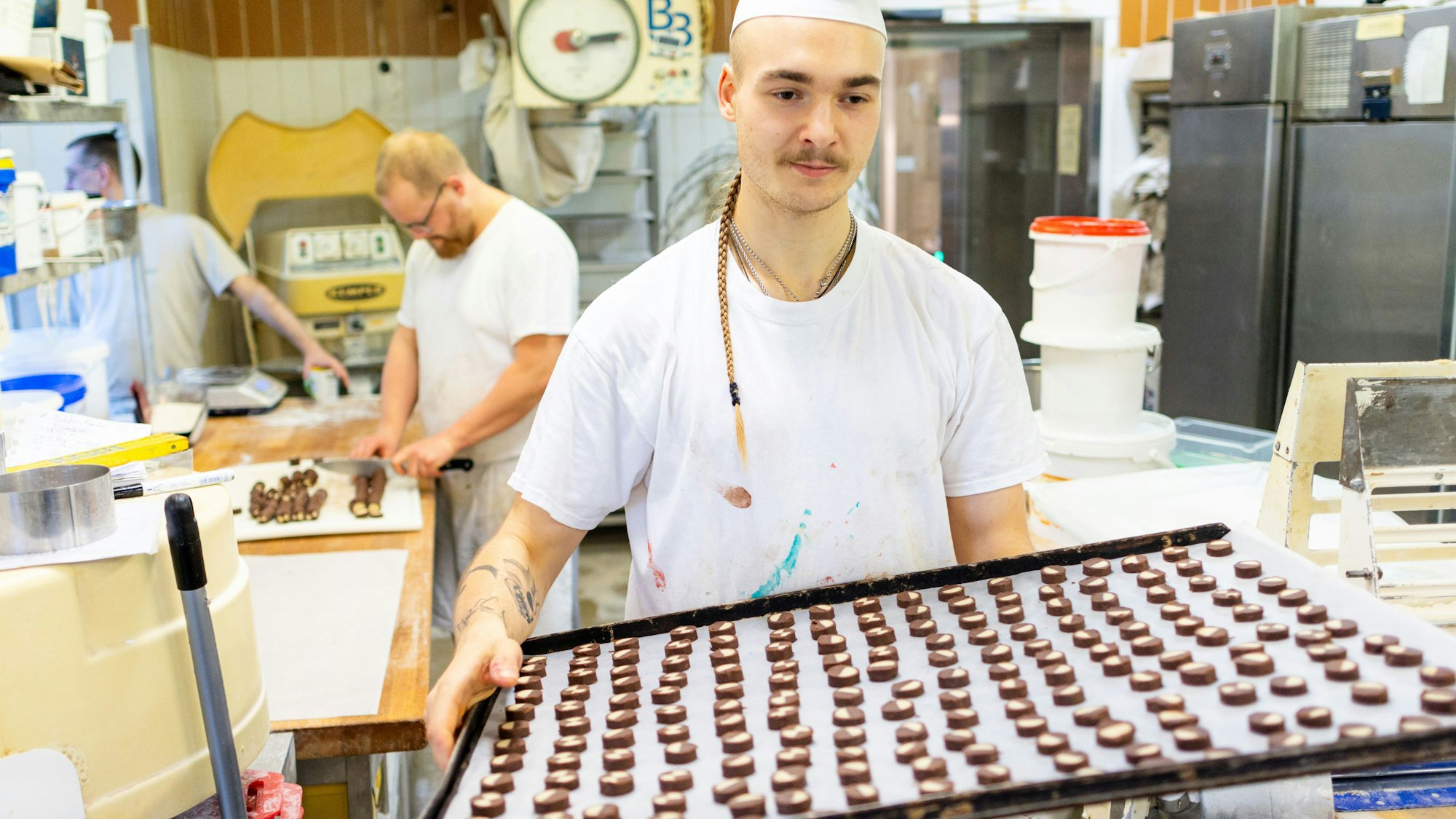 Der Bäcker Louis Braun trägt in der Bäckerei und Konditorei Lobenstein ein Blech voller Plätzchen zum Backofen.
