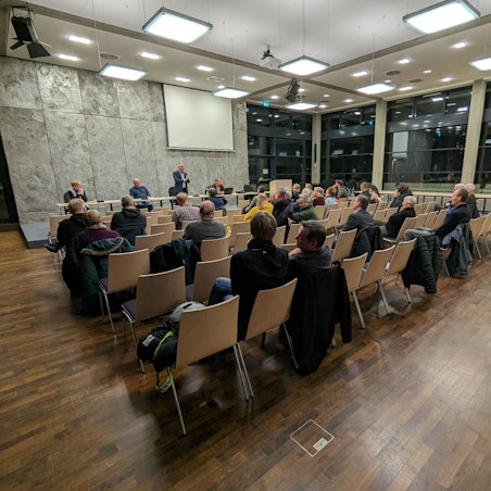 Bürger sitzen im Ratssaal von Roisdorf, vorne steht Bürgermeister Christoph Becker.