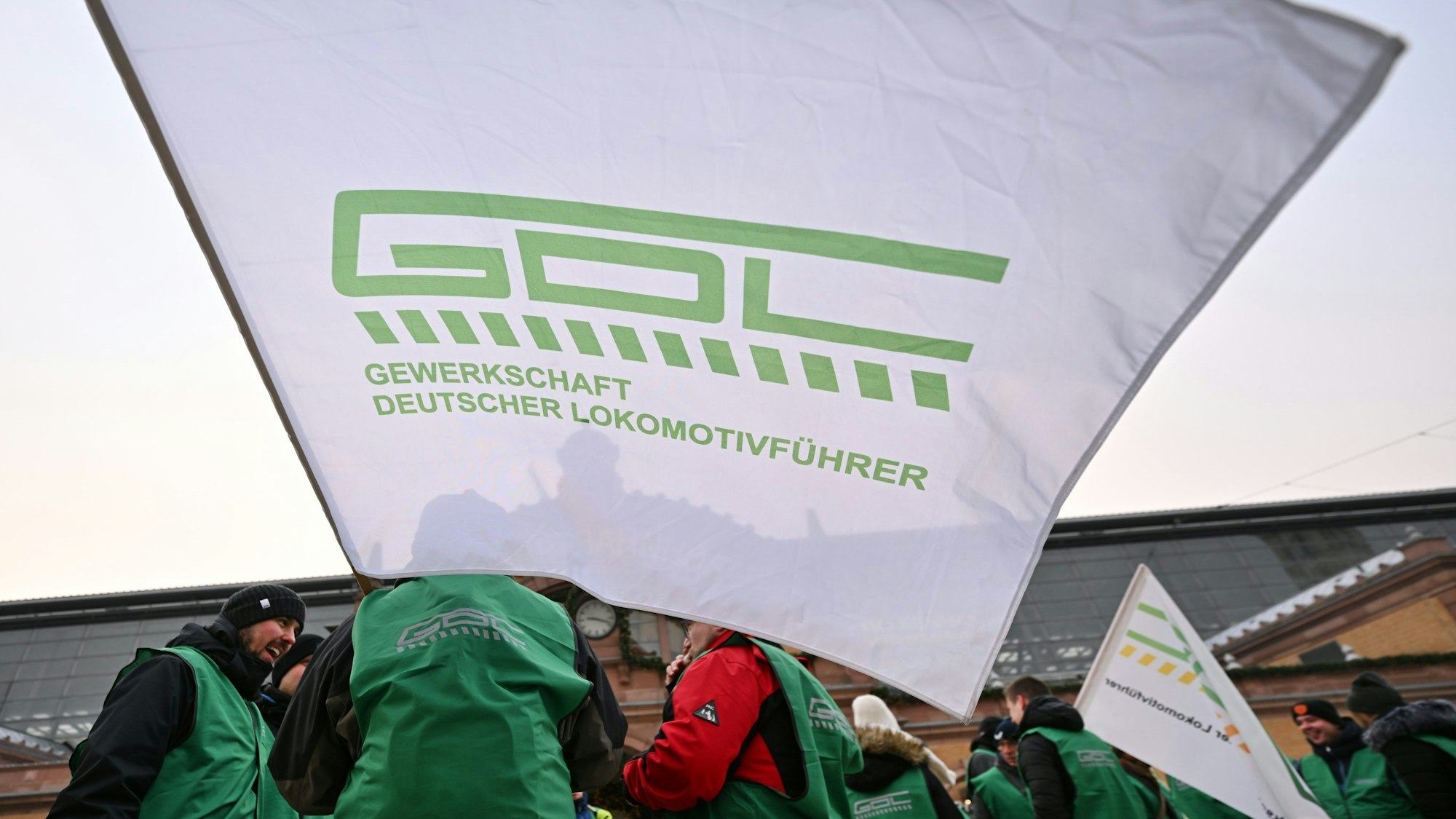 ARCHIV - 10.01.2024, Thüringen, Erfurt: Mitglieder der Lokführergewerkschaft GDL stehen mit Fahnen vor dem Erfurter Hauptbahnhof. (zu dpa: «GDL beendet Streik bei Transdev vorzeitig - Verhandlungen geplant») Foto: Martin Schutt/dpa +++ dpa-Bildfunk +++