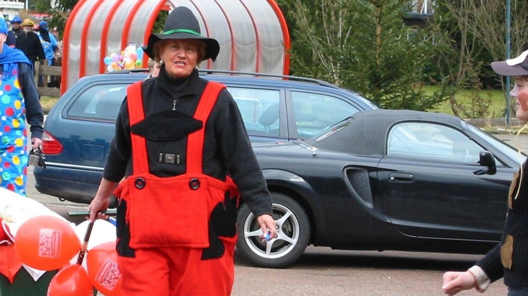 Eine verkleidete Frau zieht einen Bollerwagen hinter sich her.