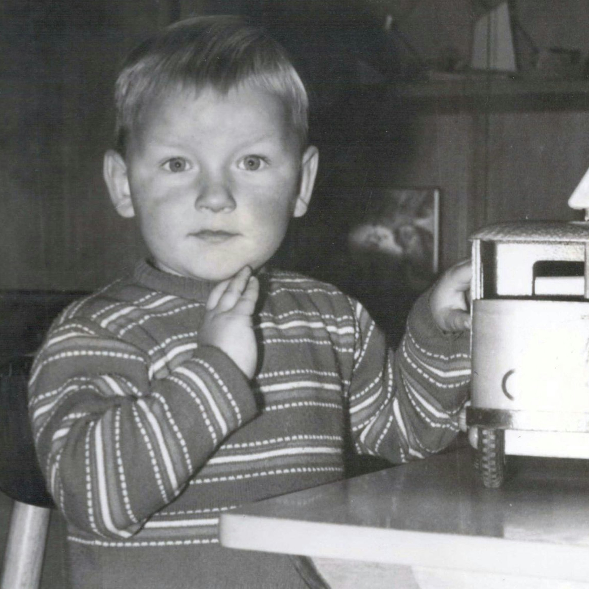 Ein Kind sitzt an einem Tisch vor einem Spielzeuglastwagen.