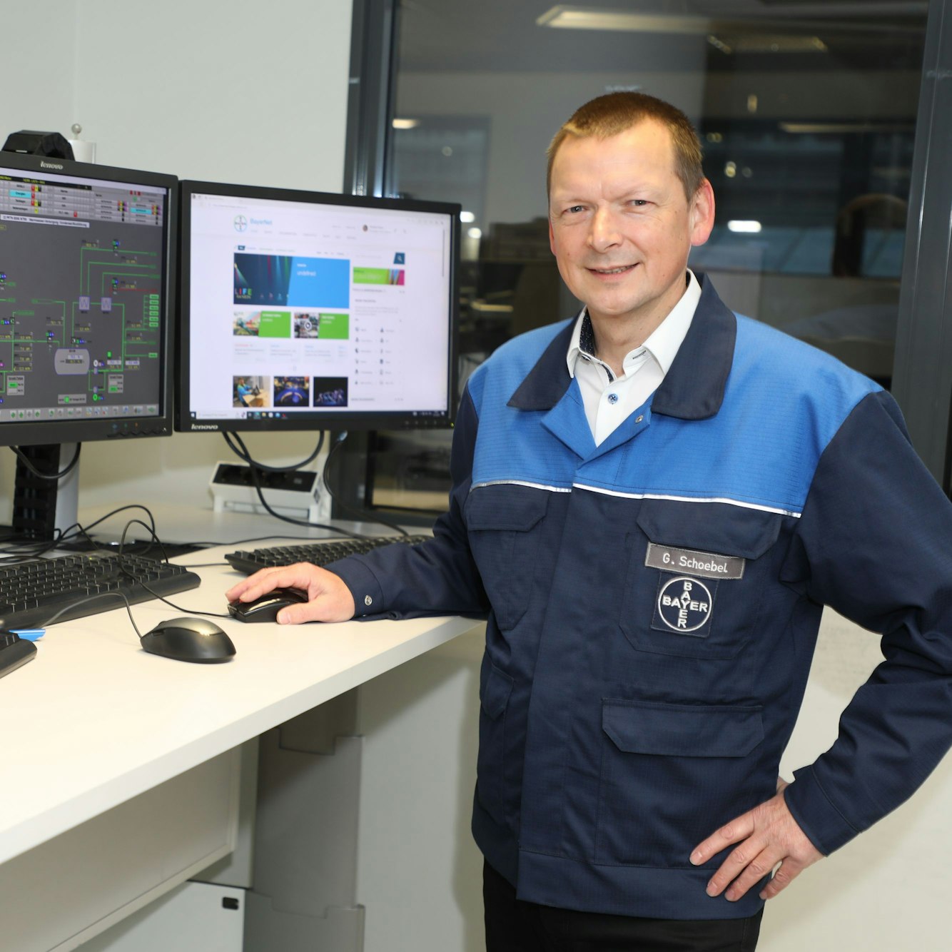 Gerd Schöbel steht an Computerbildschirmen auf einem hohen Schreibtisch.