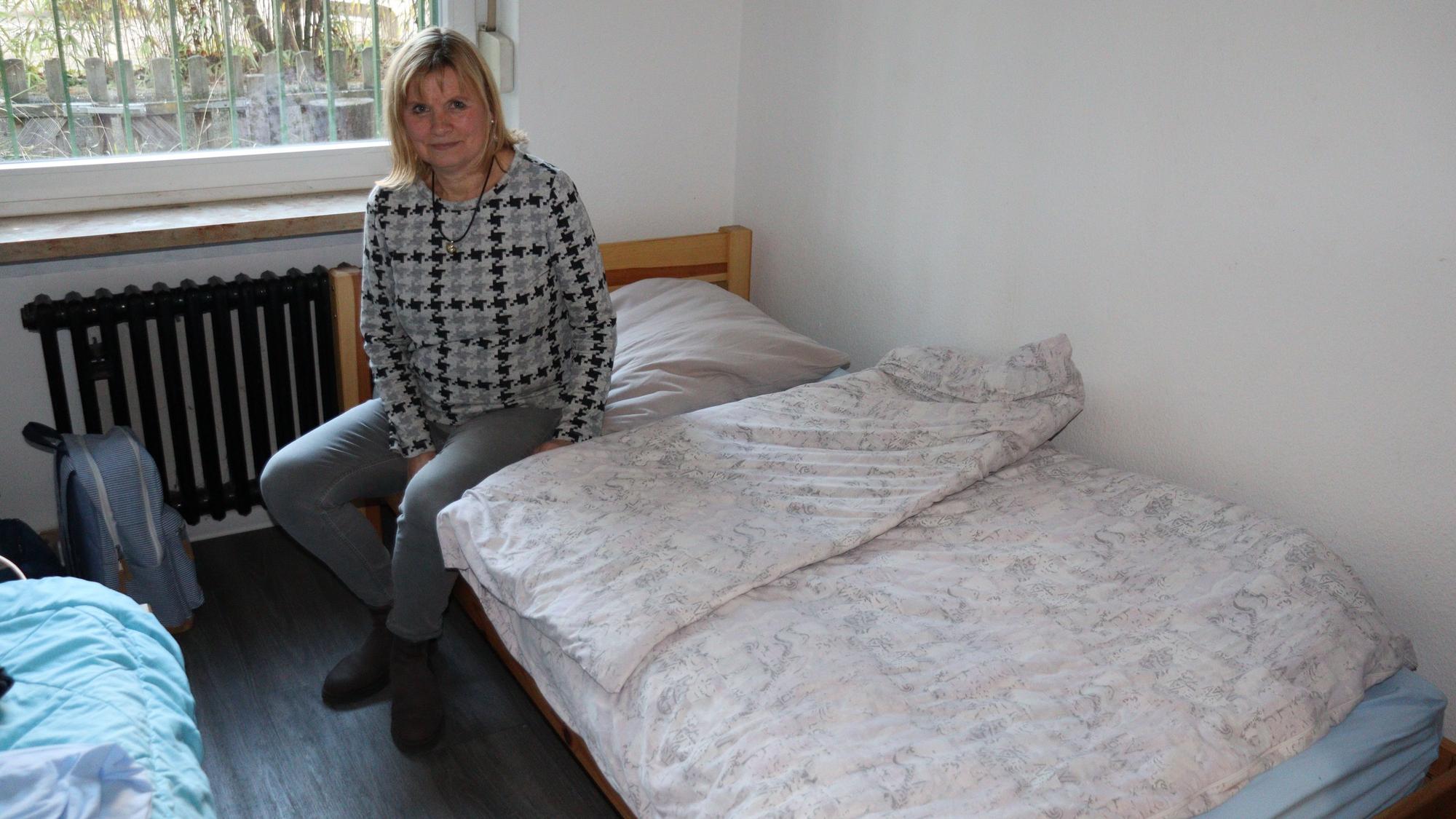 Eine Frau sitzt auf einem Bett.