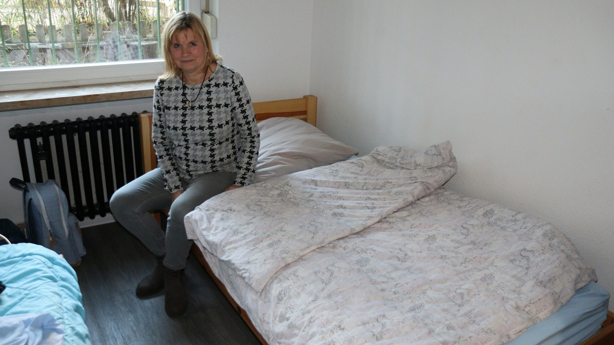 Eine Frau sitzt auf einem Bett.