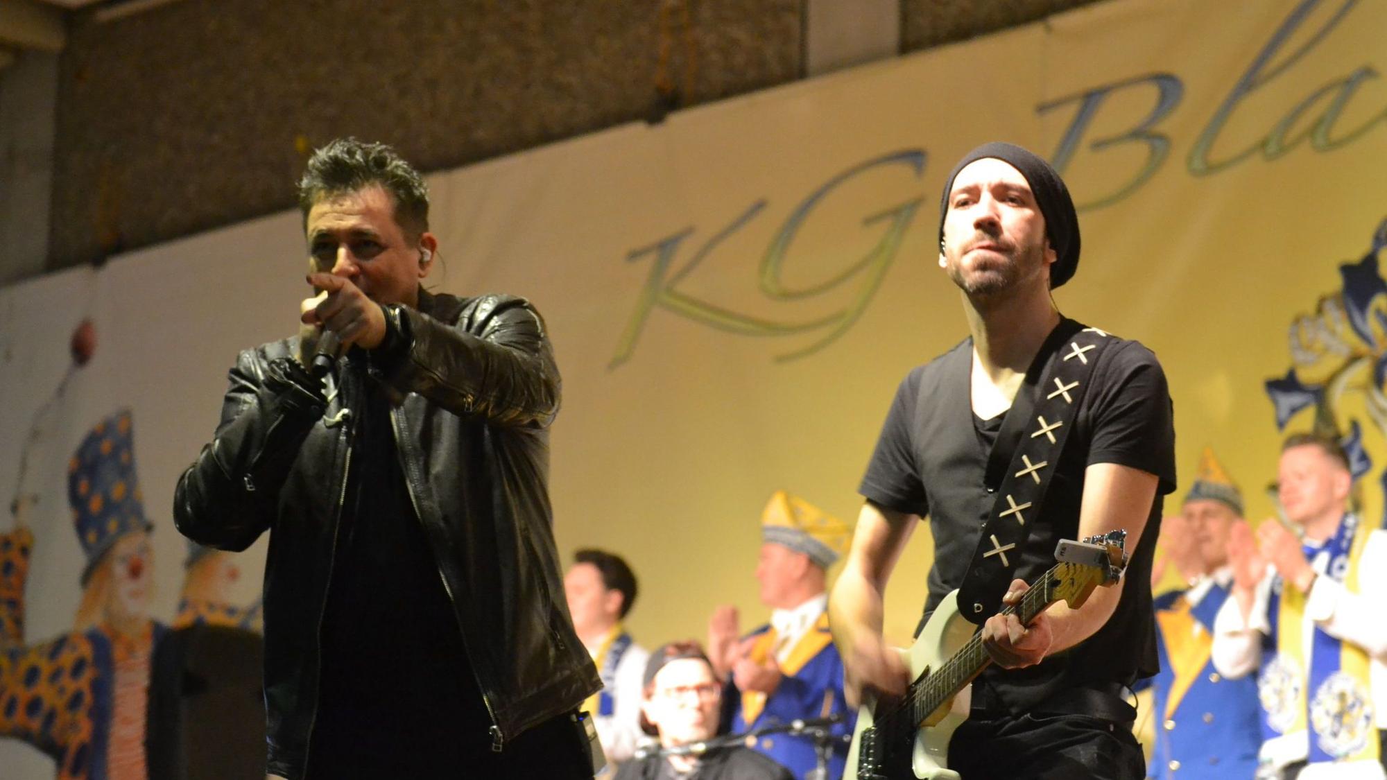 Der Sänger der Gruppe Domstürmer, Micky Nauber, auf der Karnevalsbühne in Weilerswist, neben ihm ein Gitarrist der Band, im Hintergrund Mitglieder des Elferrats.
