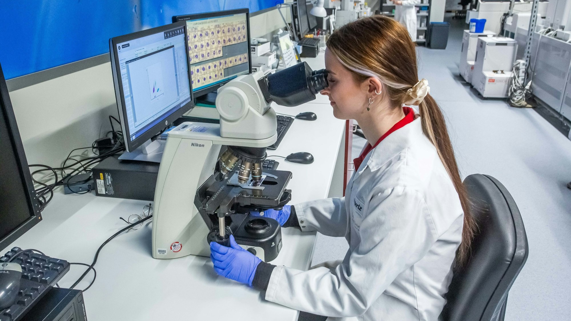 Eine junge Frau schaut in ein Mikroskop.