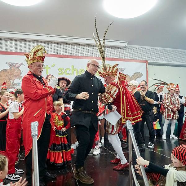 Bürgermeister Ingo Pfennings und der Gemünder Prinz Carlos Emunds tanzen auf der Bühne, auf der zahlreiche weitere Karnevalisten zu sehen sind.
