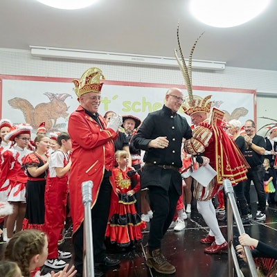 Bürgermeister Ingo Pfennings und der Gemünder Prinz Carlos Emunds tanzen auf der Bühne, auf der zahlreiche weitere Karnevalisten zu sehen sind.