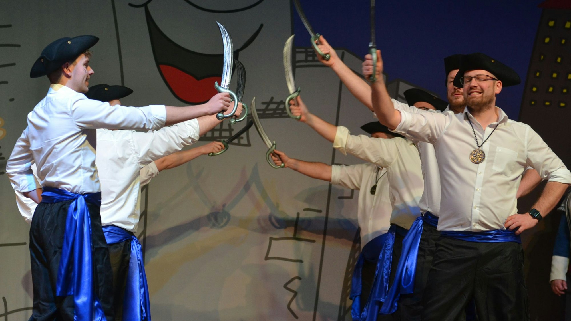 Als Piraten verkleideten Tänzer, die sich auf der Bühne gegenüberstehen, kreuzen ihre Plastiksäbel.