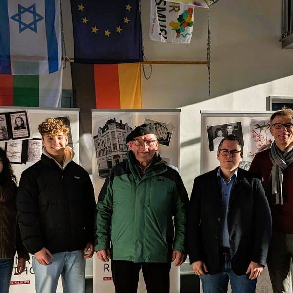 Bei der Eröffnung stehen Schüler, Lehrer und Bürgermeister Sascha Solbach vor den Ausstellungswänden.