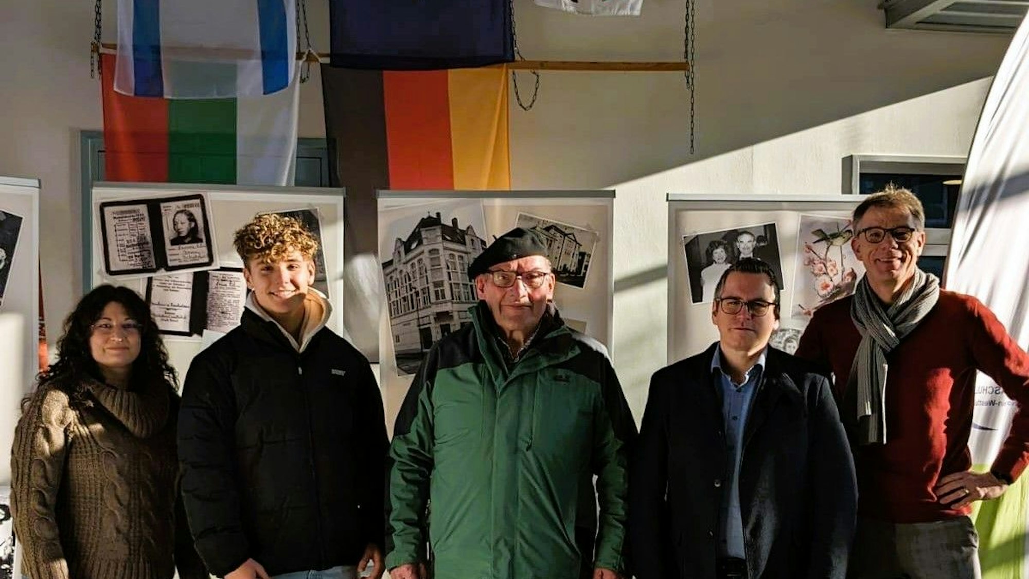 Bei der Eröffnung stehen Schüler, Lehrer und Bürgermeister Sascha Solbach vor den Ausstellungswänden.