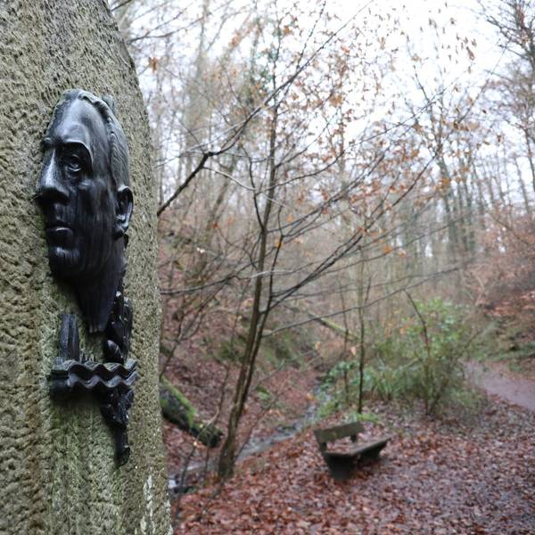 An einem großen Stein ist Bronzerelief mit einem Porträt von Willi Ostermann angebracht.